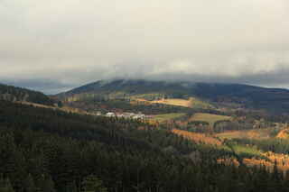 Mlhou zahalený vrchol kopce Plošina (972 m n.m.), pod ním vesnice Šukačka