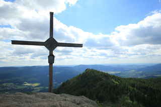 Vrcholový kříž na vrcholu hory Velký Ostrý (1293 m n.m.), za ním je vidět vrchol Malého Ostrého (1266 m n.m.)
