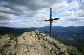 Vrcholový kříž na vrcholu hory Velký Ostrý (1293 m n.m.), přesně za ním jsou vidět vrcholy Velkého a Malého Javoru (1456 m n.m. a 1384 m n.m.)